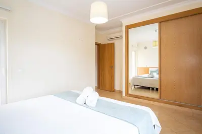 a bedroom with a white bed and a mirror at Apartment Hugo - Complex perfect for families in Albufeira