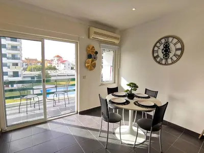a dining room with a table and chairs and a clock at Vilamoura Neptuno in Quarteira