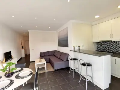 a kitchen and living room with a couch and a table at Vilamoura Neptuno in Quarteira