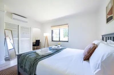 a white bedroom with a large bed and a desk at Muito Sol in Albufeira