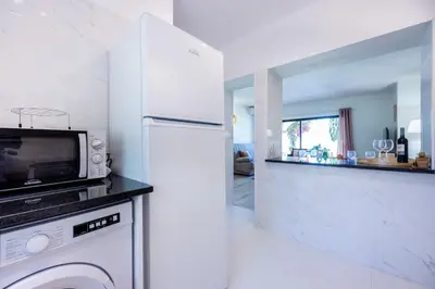 a white kitchen with a microwave and a dishwasher at Muito Sol in Albufeira