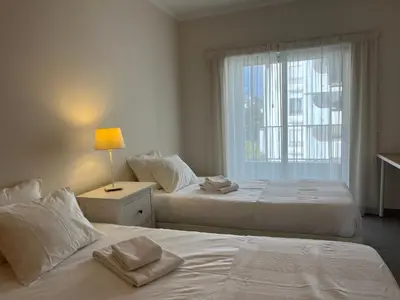 two beds in a white room with a window at Pure Sea - Beach Apartment in Quarteira