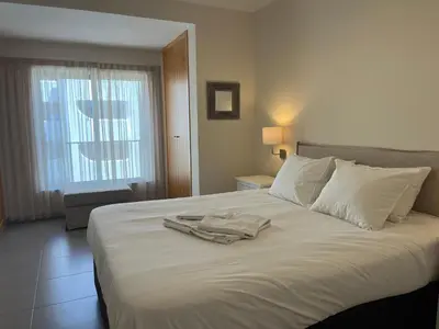 a white bed with a robe on top of it at Pure Sea - Beach Apartment in Quarteira