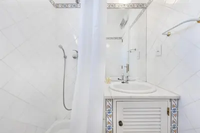a white bathroom with a sink and a shower at Villa Luz do Atlantico by OCvillas in Galé
