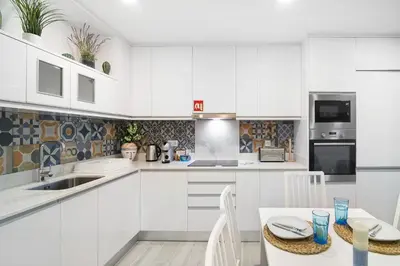 a kitchen with white cabinets and a table and chairs at Apartamento Acácia in Vale do Lobo