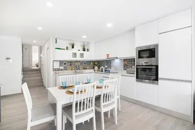 a kitchen with white cabinets and a table and chairs at Apartamento Acácia in Vale do Lobo