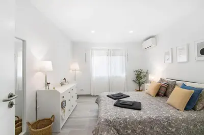 a white bedroom with a bed and a dresser at Apartamento Acácia in Vale do Lobo