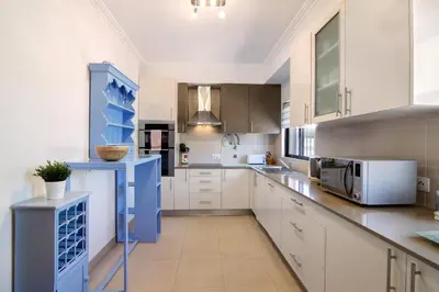 a kitchen with white cabinets and a blue counter top at Villa Formosa in Almancil