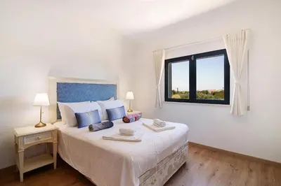 a white bedroom with a large bed with a window at Villa Formosa in Almancil