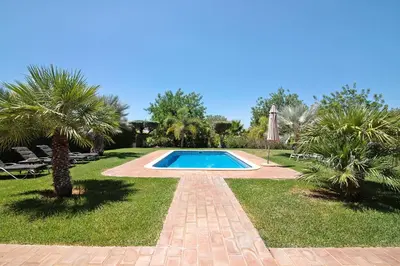 a swimming pool in a yard with palm trees at Villa Formosa in Almancil