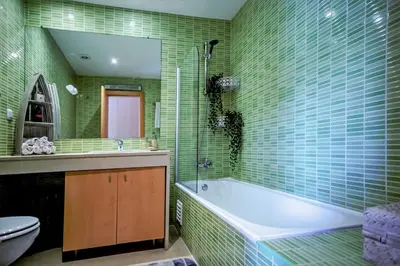 a bathroom with a tub and a toilet and green tiles at Luxury Apartment with Pool in Albufeira