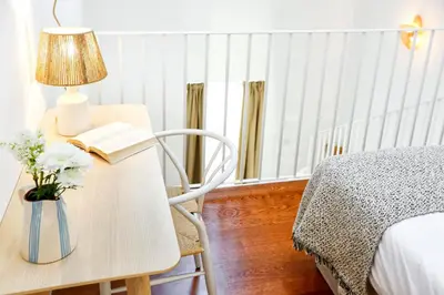 a bedroom with a desk with a lamp and a book at Watermelon Sugar Apartment in Faro