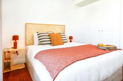 a bedroom with a large white bed with orange pillows at Watermelon Sugar Apartment in Faro