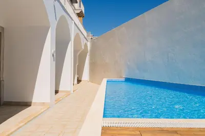 a blue swimming pool next to a white building at Under the moon in Faro