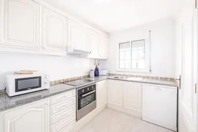 a white kitchen with white cabinets and a microwave at Apartment Maria - Complex with tennis court and restaurant,pool in Albufeira