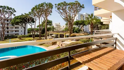 a balcony with a swimming pool and a wooden bench at Sweet As by LovelyStay in Quarteira