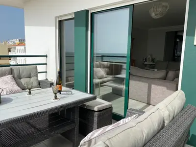 a balcony with a table and chairs and a living room at Seaview & Sunsets Apartment in Quarteira