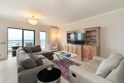 a living room with a couch and a tv at Seaview & Sunsets Apartment in Quarteira
