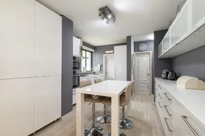 a kitchen with white cabinets and a white table at Seaview & Sunsets Apartment in Quarteira