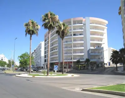 an empty street with palm trees in front of a building at Beach Lover's Paradise: 3BR 2 min from the Sand in Quarteira