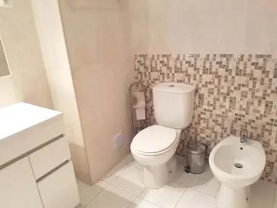 a bathroom with a white toilet and a sink at Seaside Serenity: 1BR with Breathtaking Ocean View in Quarteira