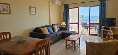 a living room with a blue couch and a table and a dining room at Seaside Serenity: 1BR with Breathtaking Ocean View in Quarteira
