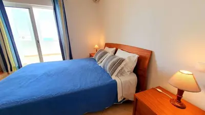 a small bedroom with a blue bed and a lamp at Quarteira Beach Vacation: 2BR steps to the sand in Quarteira