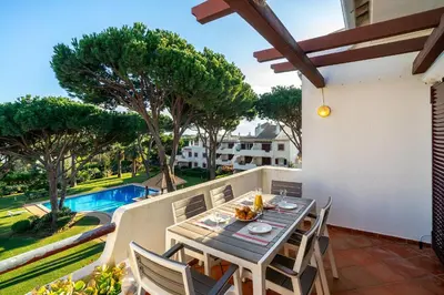 a patio with a table and chairs and a pool at Family Apartment Pool & Terrace in Vilamoura