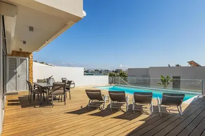 a deck with a table and chairs next to a swimming pool at Villa Jasmim by OCvillas in Albufeira