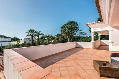 an outdoor patio with a white wall and palm trees at Villa Zarana fantastic house in Salinas in Faro