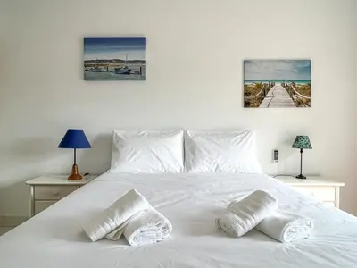 a bedroom with a white bed with three pictures on the wall at Lovely Apartment in Albufeira 2BD 250m Beach Ocean view and AC Wi-Fi Pool in Albufeira
