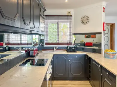 a kitchen with black cabinets and a clock on the wall at Lovely Apartment in Albufeira 2BD 250m Beach Ocean view and AC Wi-Fi Pool in Albufeira