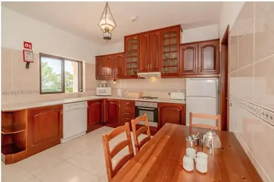 a kitchen with wooden cabinets and a wooden table at Villa Alegria in Loulé