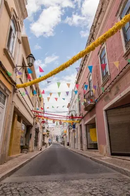 an empty street with flags and bunting hanging between buildings at Villa Alegria in Loulé