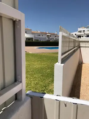 a white fence and a field of green grass at Cozy apartment near Oura Beach in Albufeira