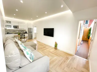 a living room with a white couch and a kitchen at So Sweet Center of Faro Flat in Faro
