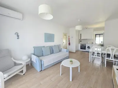 a living room with a couch and a tv and a table at Modern Beach Apartment - Avenida Mar 1 - 150 mts da praia in Quarteira