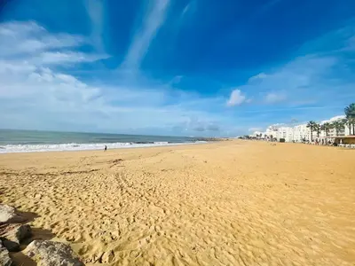 a beach with a person walking on the sand at Modern Beach Apartment - Avenida Mar 1 - 150 mts da praia in Quarteira