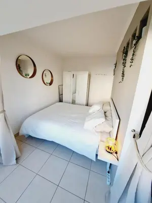 a bedroom with a white bed and a mirror at T1, proche plage et commerces in Quarteira