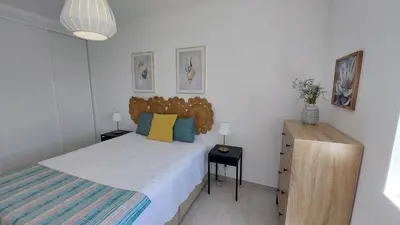 a bedroom with a bed and a wooden dresser at Apartamento Kélyfos Beach by feriascomsol in Quarteira