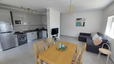 a kitchen and living room with a table and a couch at Apartamento Kélyfos Beach by feriascomsol in Quarteira