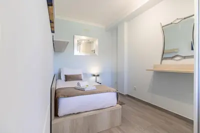 a small bedroom with a bed and a mirror at Apartamento King in Vilamoura