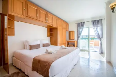 a bedroom with a large bed and a large window at Apartamento King in Vilamoura