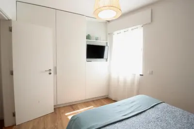 a white bedroom with a bed and a tv at Downtown Villa in Faro