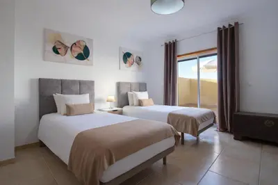 a hotel room with two beds and a window at Apartamento Alameda in Quarteira