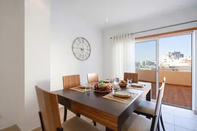 a dining room with a table and a clock on the wall at Apartamento Alameda in Quarteira