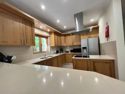 a kitchen with wooden cabinets and a stainless steel refrigerator at Villa Pedra Luxe - Spacious modern villa in Albufeira