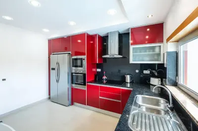 a kitchen with red cabinets and a stainless steel refrigerator at Villa Adaro - Large Luxury close to marina in Albufeira