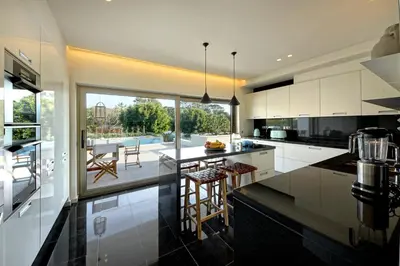 a kitchen with white cabinets and a large window at Luxury Beach Villa - Casa do Forte- Infinity Pool sea view- Beach walking distance by DreamvillasAlbufeira in Albufeira