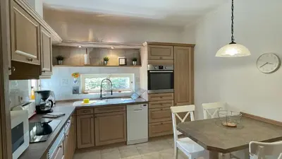a kitchen with wooden cabinets and a table with a sink at Falesia by Check-in Portugal in Albufeira